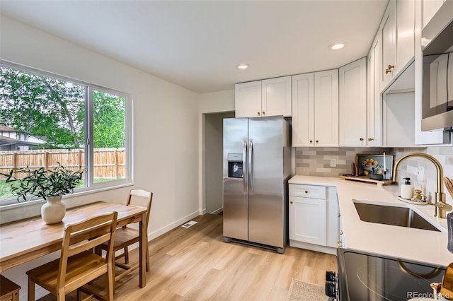 14317 Olmsted Dr, Denver, CO 80239 - kitchen featuring appliances with stainless steel finishes, a sink, light countertops, light wood-style flooring, and decorative backsplash