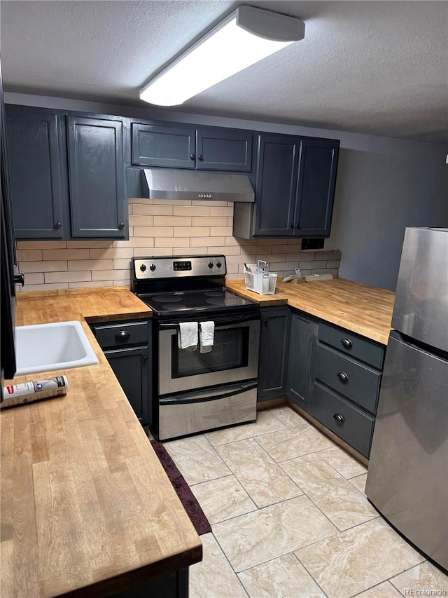 kitchen featuring backsplash, sink, a textured ceiling, appliances with stainless steel finishes, and butcher block countertops