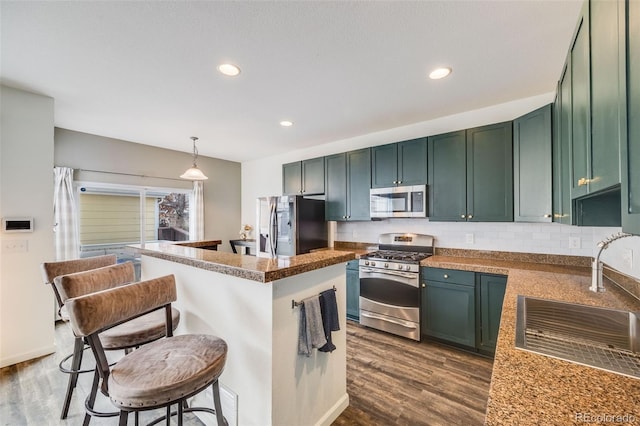 22765 E Ottawa Pl, Aurora, CO 80016 - kitchen featuring appliances with stainless steel finishes, a kitchen bar, dark wood-type flooring, green cabinets, and recessed lighting