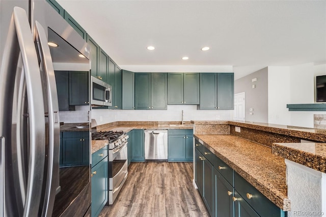 22765 E Ottawa Pl, Aurora, CO 80016 - kitchen with appliances with stainless steel finishes, wood finished floors, recessed lighting, green cabinetry, and backsplash