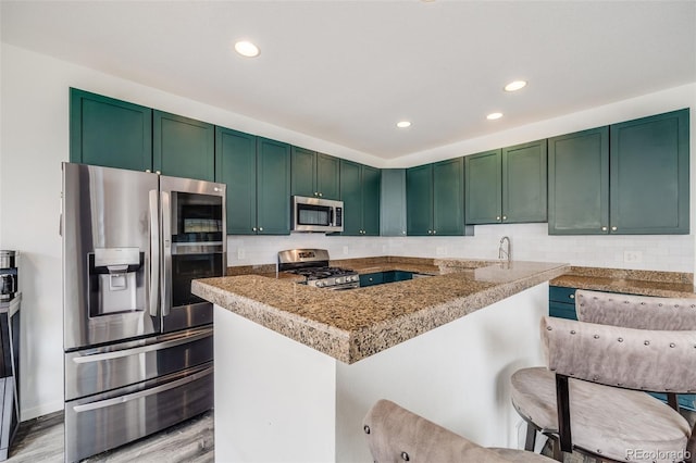 22765 E Ottawa Pl, Aurora, CO 80016 - kitchen featuring stainless steel appliances, tasteful backsplash, recessed lighting, light wood-style flooring, and a kitchen breakfast bar