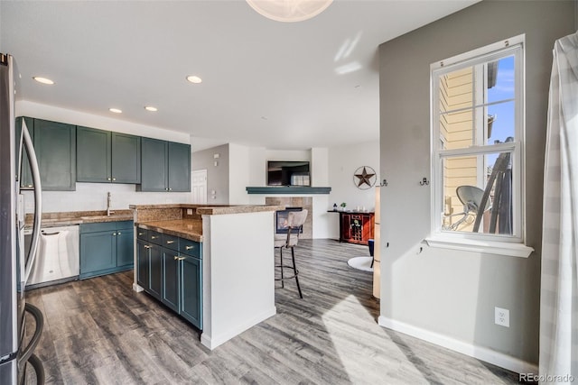 22765 E Ottawa Pl, Aurora, CO 80016 - kitchen with stainless steel appliances, dark wood-type flooring, a center island, a kitchen bar, and recessed lighting