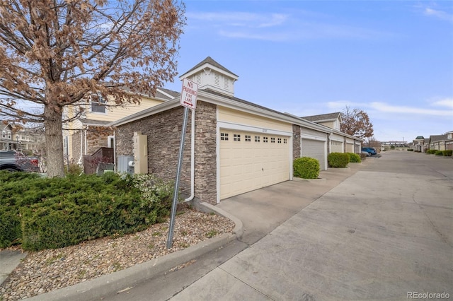 22765 E Ottawa Pl, Aurora, CO 80016 - view of side of home with concrete driveway, stone siding, and an attached garage