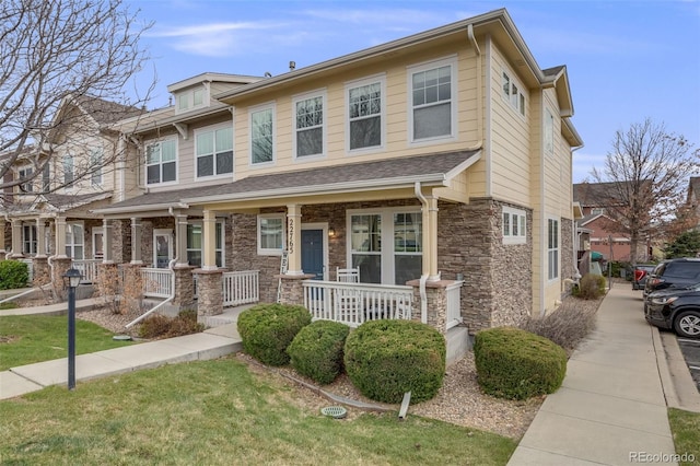 22765 E Ottawa Pl, Aurora, CO 80016 - townhome / multi-family property with stone siding and covered porch