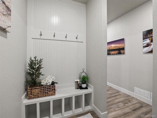 mudroom with a textured wall, wood finished floors, visible vents, and baseboards