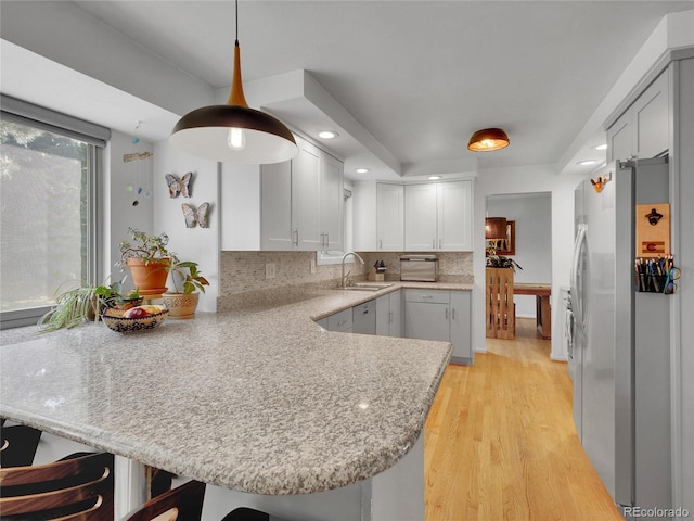 4720 W Stanford Ave, Denver, CO 80236 - kitchen featuring stainless steel fridge, a peninsula, light wood-style flooring, decorative backsplash, and recessed lighting