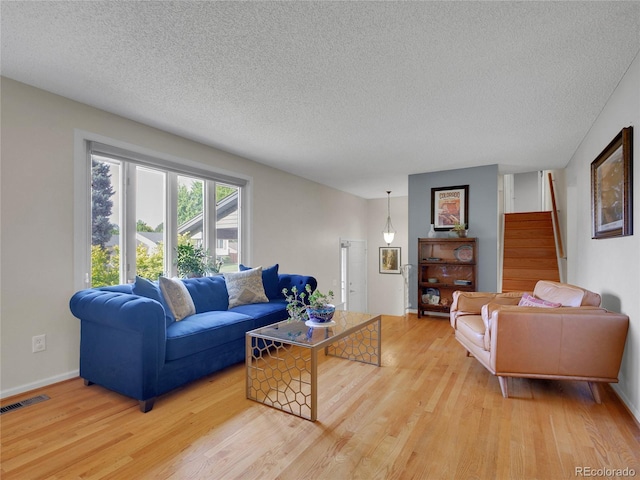 4720 W Stanford Ave, Denver, CO 80236 - living room featuring light wood-style flooring, a textured ceiling, and stairs