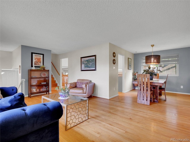 4720 W Stanford Ave, Denver, CO 80236 - living room featuring light wood-type flooring, a textured ceiling, and stairway
