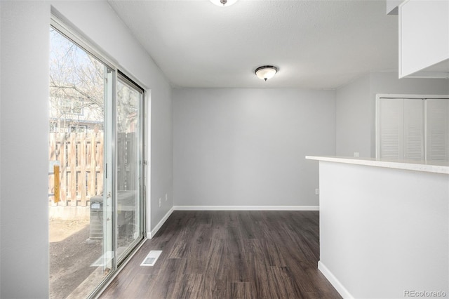 unfurnished room featuring dark wood-type flooring and baseboards