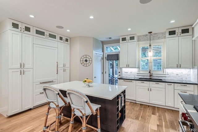 2436 W Argyle Pl, Denver, CO 80211 - kitchen with a sink, light wood-style flooring, decorative backsplash, white cabinetry, and recessed lighting