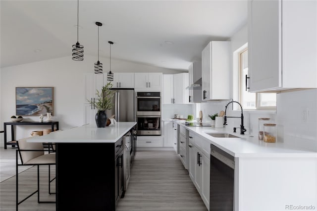 8249 Zephyr St, Arvada, CO 80005 - kitchen featuring appliances with stainless steel finishes, lofted ceiling, a kitchen bar, backsplash, and light countertops