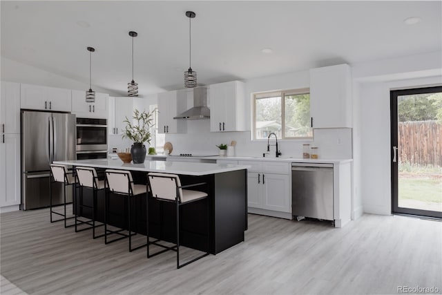 8249 Zephyr St, Arvada, CO 80005 - kitchen with stainless steel appliances, wall chimney range hood, a breakfast bar, light countertops, and a center island