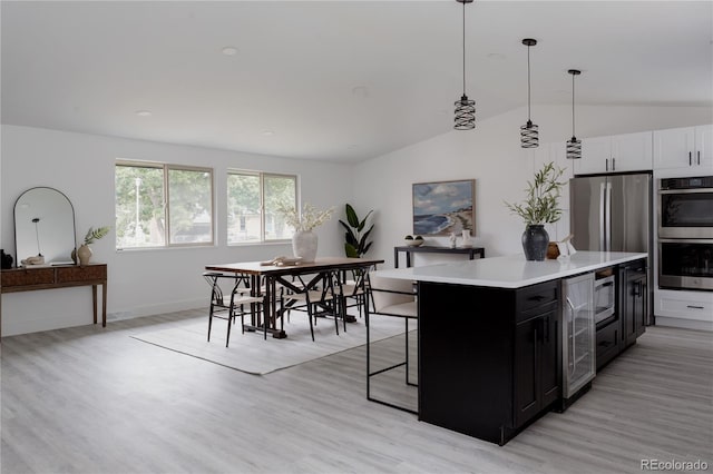 8249 Zephyr St, Arvada, CO 80005 - kitchen with wine cooler, stainless steel appliances, dark cabinetry, vaulted ceiling, and light countertops