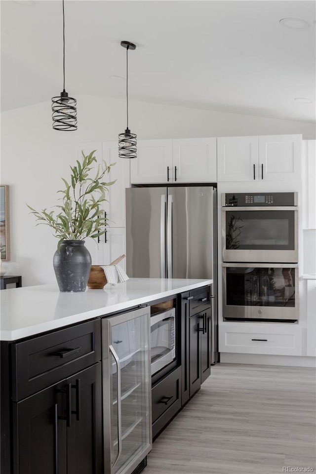 8249 Zephyr St, Arvada, CO 80005 - kitchen featuring beverage cooler, appliances with stainless steel finishes, vaulted ceiling, light countertops, and light wood-style flooring