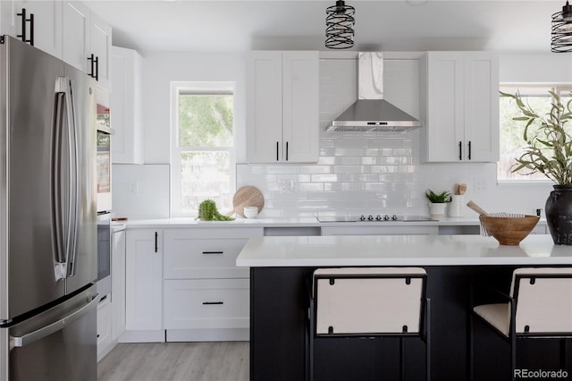 8249 Zephyr St, Arvada, CO 80005 - kitchen featuring freestanding refrigerator, wall chimney exhaust hood, black electric cooktop, light countertops, and tasteful backsplash
