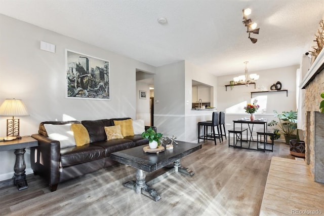 living room with hardwood / wood-style floors, a textured ceiling, and an inviting chandelier