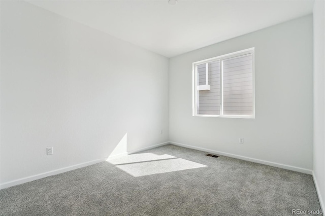 unfurnished room featuring carpet, visible vents, and baseboards