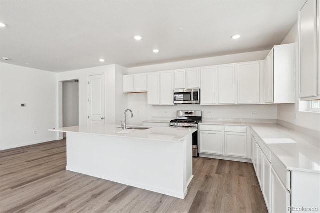 kitchen featuring an island with sink, a sink, recessed lighting, appliances with stainless steel finishes, and light wood finished floors