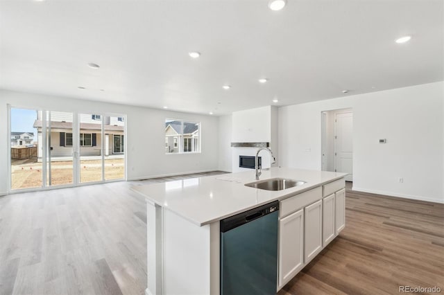 kitchen featuring light wood-type flooring, a kitchen island with sink, a sink, open floor plan, and dishwasher