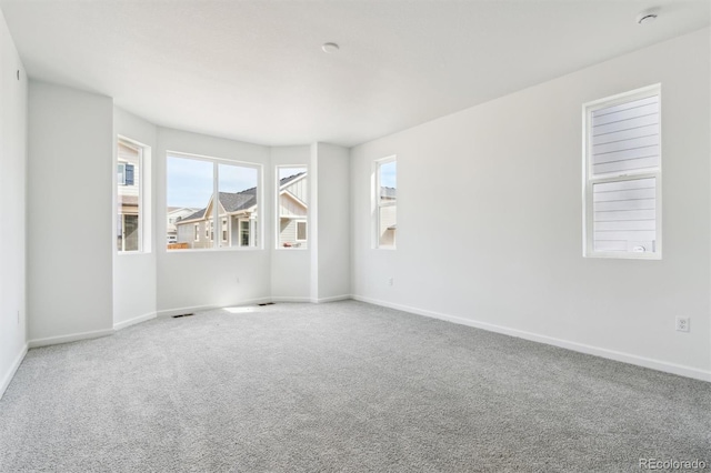 carpeted spare room with visible vents and baseboards