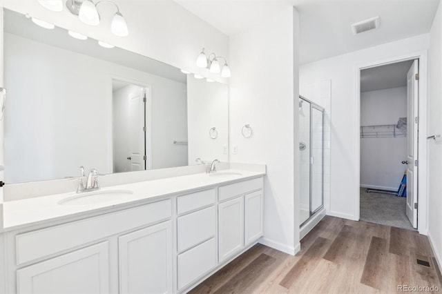 full bathroom featuring visible vents, a shower stall, wood finished floors, and a sink