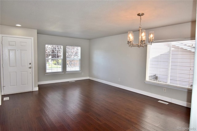 unfurnished room with a chandelier and dark hardwood / wood-style floors