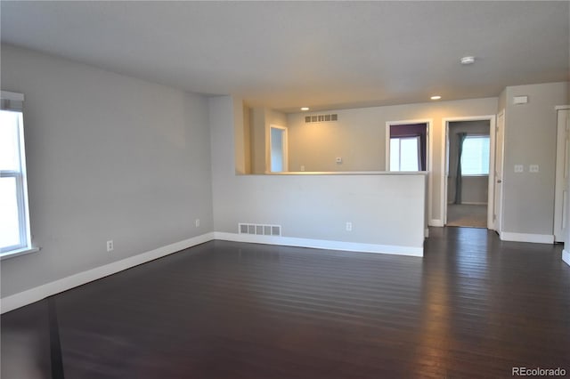 spare room featuring dark wood-type flooring and plenty of natural light