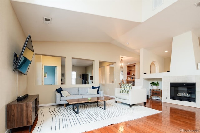 7777 E 23rd Ave Unit 1202, Denver, CO 80238 - living room featuring wood-type flooring, built in shelves, vaulted ceiling, and a tile fireplace