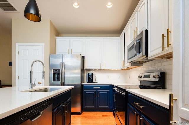 7777 E 23rd Ave Unit 1202, Denver, CO 80238 - kitchen with appliances with stainless steel finishes, blue cabinetry, light wood-type flooring, white cabinets, and recessed lighting