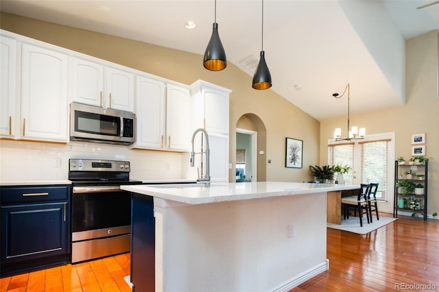 7777 E 23rd Ave Unit 1202, Denver, CO 80238 - kitchen with stainless steel appliances, blue cabinetry, arched walkways, light wood-type flooring, and vaulted ceiling