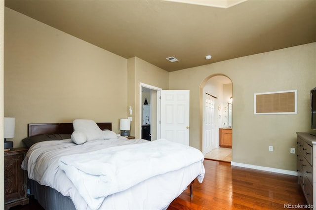 7777 E 23rd Ave Unit 1202, Denver, CO 80238 - bedroom featuring arched walkways, wood finished floors, and ensuite bath