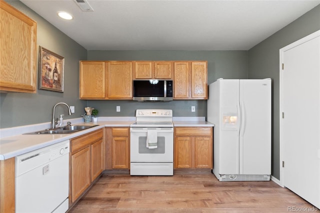 kitchen featuring light wood-style flooring, a sink, visible vents, white appliances, and light countertops