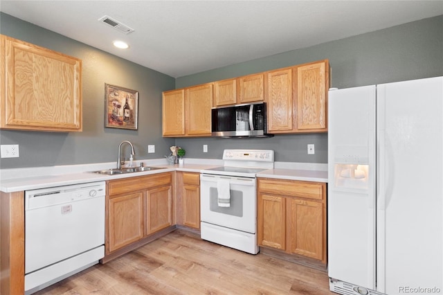 kitchen with light countertops, visible vents, a sink, white appliances, and light wood-type flooring