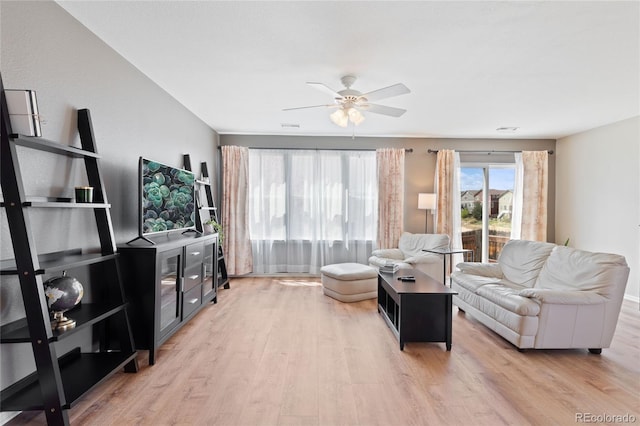 living room with light wood-style flooring, visible vents, and a ceiling fan