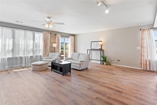 living room with track lighting, a ceiling fan, wood finished floors, and visible vents