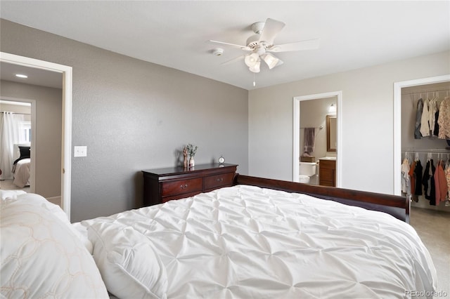 carpeted bedroom with a walk in closet, a closet, a ceiling fan, and ensuite bathroom