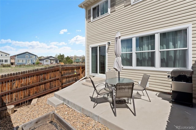 view of patio featuring fence, outdoor dining space, a grill, and a residential view