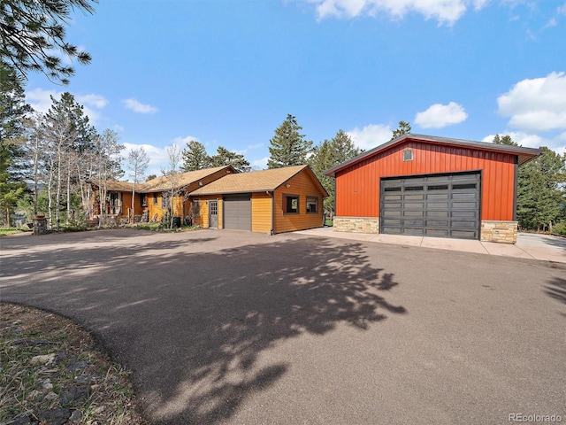 7754 Swaps Trl, Evergreen, CO 80439 - view of front facade with stone siding, a garage, board and batten siding, and an outdoor structure