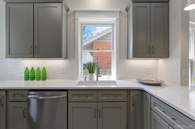 kitchen featuring sink, stainless steel dishwasher, gray cabinets, and tasteful backsplash