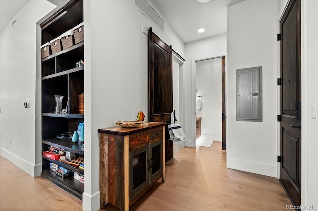 hall featuring a barn door, electric panel, and light hardwood / wood-style floors