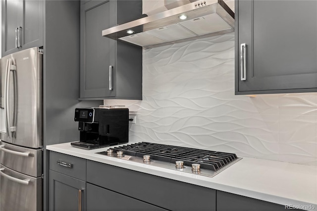 kitchen with wall chimney exhaust hood, appliances with stainless steel finishes, decorative backsplash, and gray cabinetry