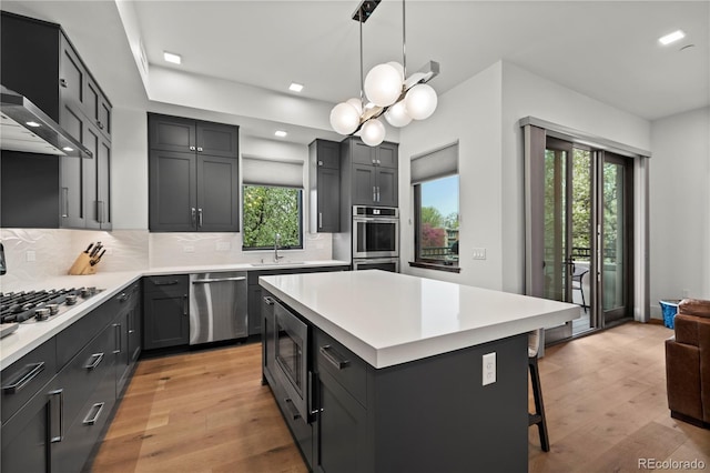 kitchen with a breakfast bar, hanging light fixtures, stainless steel appliances, tasteful backsplash, and a kitchen island