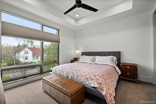 bedroom featuring a tray ceiling, carpet floors, and ceiling fan