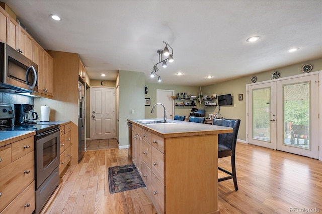 4855 E Atlantic Pl, Denver, CO 80222 - kitchen with appliances with stainless steel finishes, a sink, a breakfast bar, light brown cabinetry, and recessed lighting