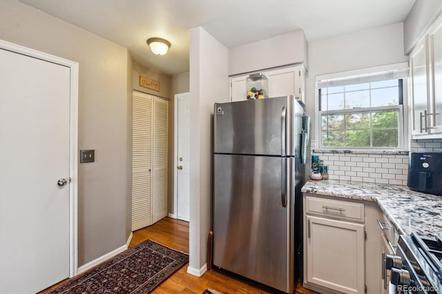 1818 S Quebec Way Unit 4, Denver, CO 80231 - kitchen with appliances with stainless steel finishes, light wood-style floors, white cabinets, decorative backsplash, and light stone countertops