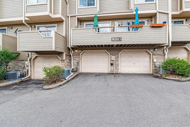 1818 S Quebec Way Unit 4, Denver, CO 80231 - view of building exterior featuring central AC, asphalt driveway, and a garage