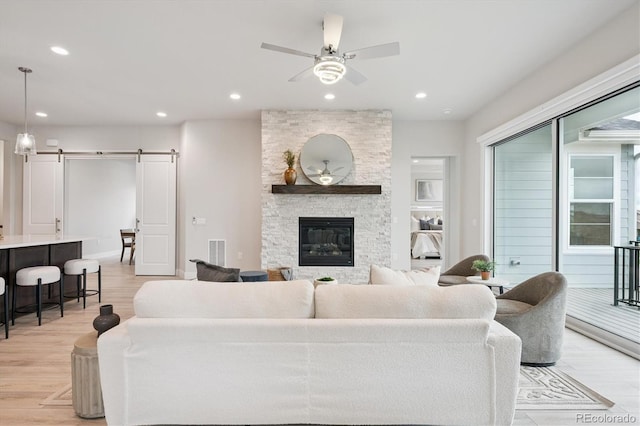 22183 E Rocky Top Pl, Aurora, CO 80016 - living room featuring a barn door, a ceiling fan, light wood-style floors, recessed lighting, and a fireplace
