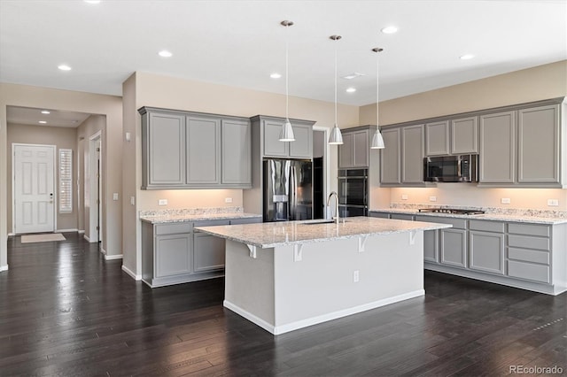 6725 Mentha Dr, Castle Rock, CO 80108 - kitchen with dark wood-style flooring, appliances with stainless steel finishes, a breakfast bar area, a kitchen island with sink, and gray cabinets
