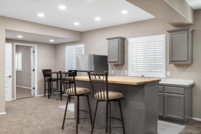 6725 Mentha Dr, Castle Rock, CO 80108 - kitchen with gray cabinetry, freestanding refrigerator, a kitchen bar, and butcher block countertops