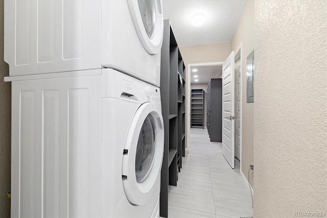 6725 Mentha Dr, Castle Rock, CO 80108 - washroom featuring laundry area, a textured wall, stacked washer / drying machine, and light tile patterned flooring